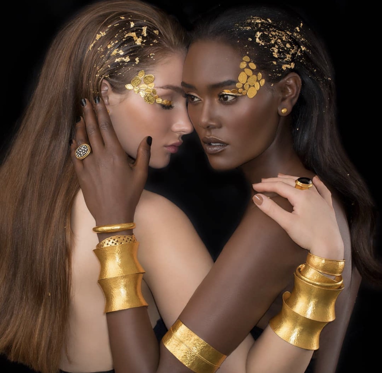 Two models wearing Yossi Harari hand-hammered 24K gold cuffs, bangles and rings