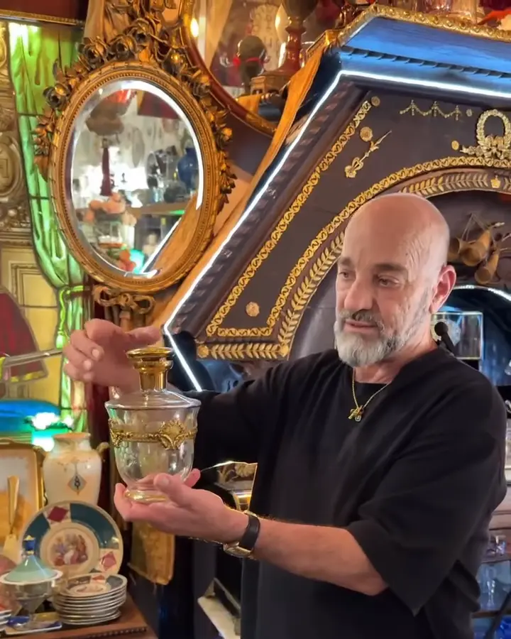 Yossi Harari standing among art, glass and collected objects inside his Jaffa maison